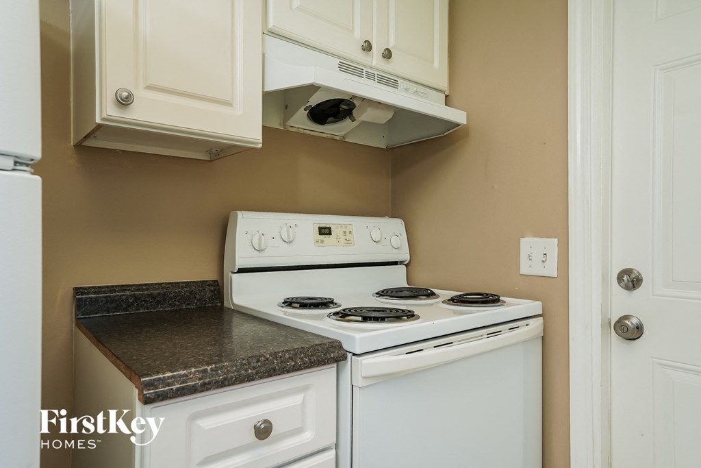 A white stove and oven in a kitchen with a white door.