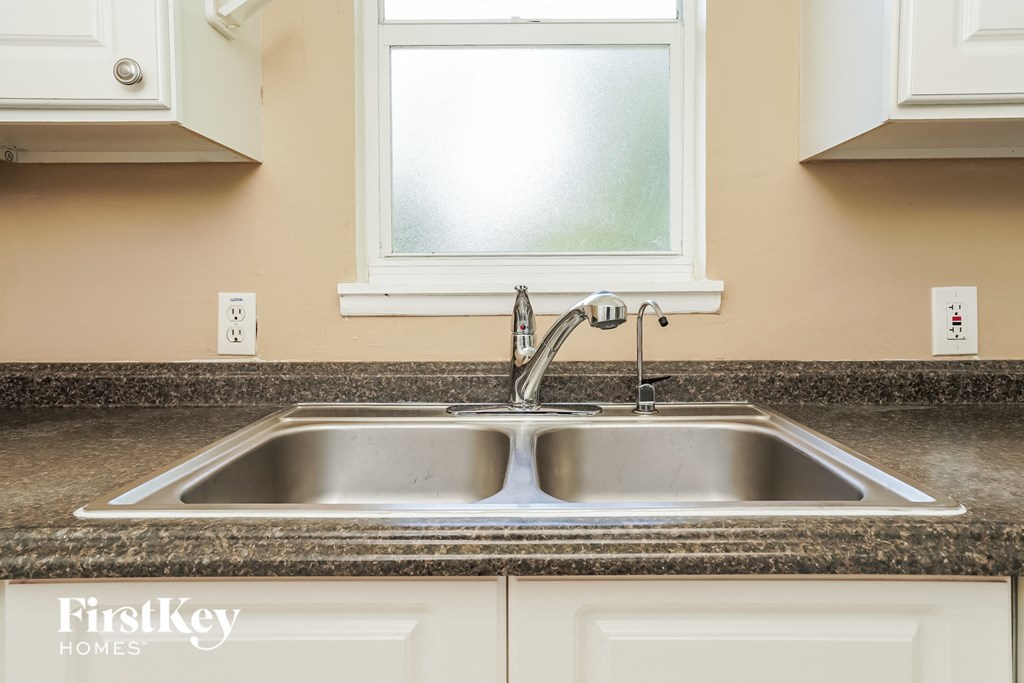 A kitchen sink with a granite counter top.