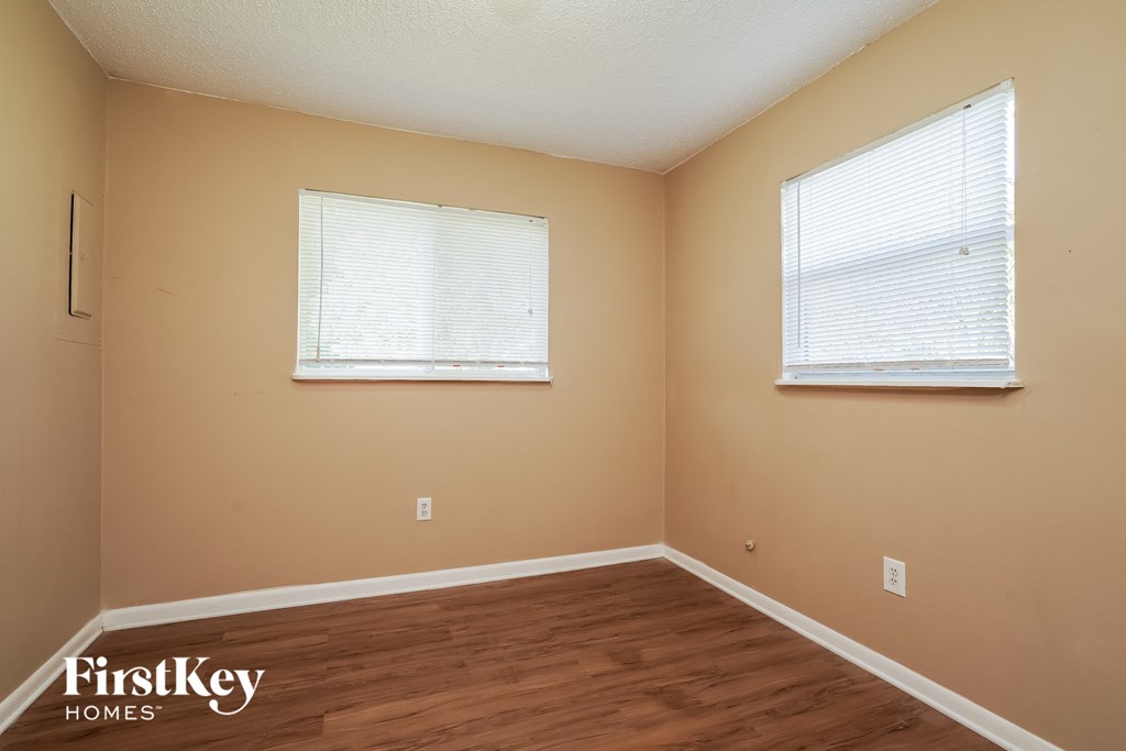 A room with wooden floors and two windows.