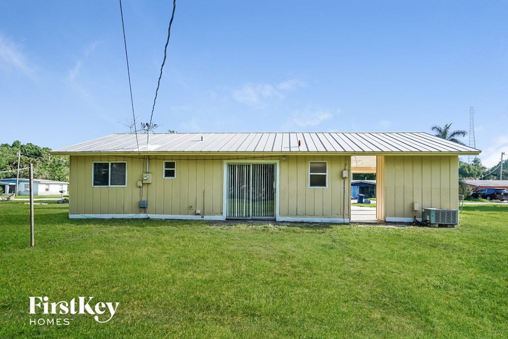 A small yellow house with a metal roof and a sign that says "FirstKey Homes".