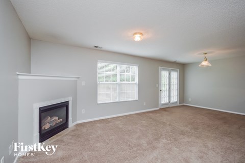 A living room with a fireplace and a carpeted floor.