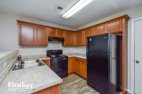 A kitchen with wooden cabinets and a black fridge.