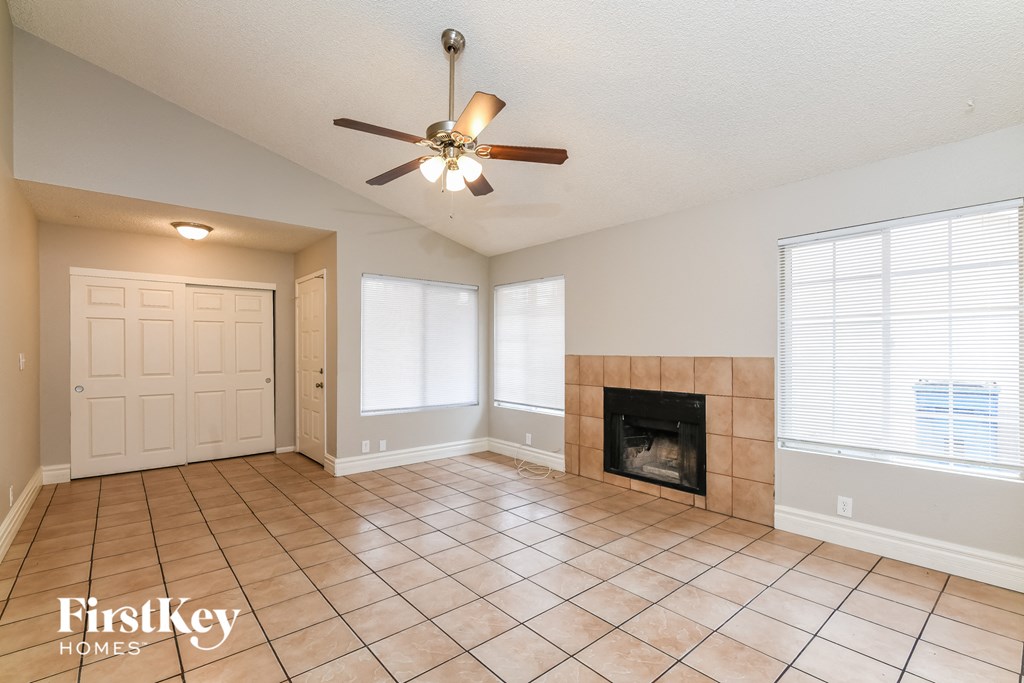 A spacious room with a fireplace and a ceiling fan.
