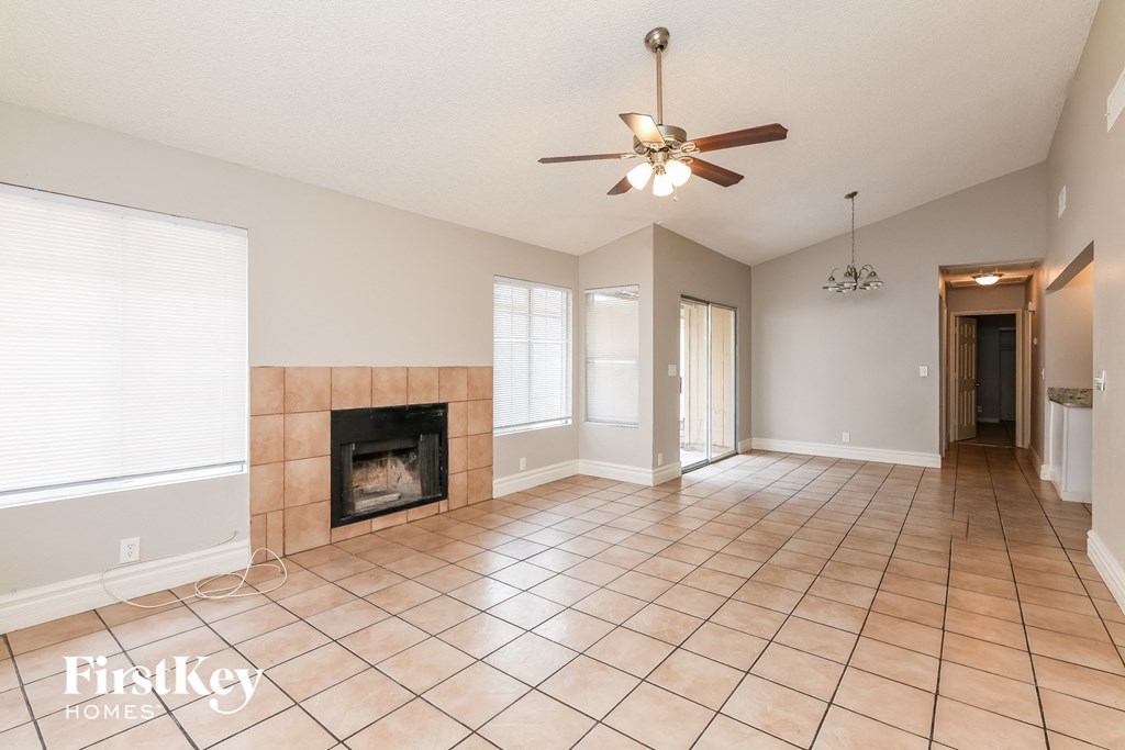A spacious living room with a fireplace and a ceiling fan.