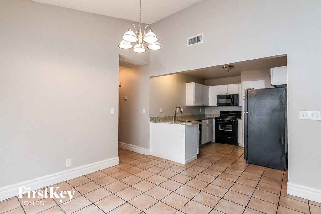 A kitchen with a black refrigerator and a white counter top.