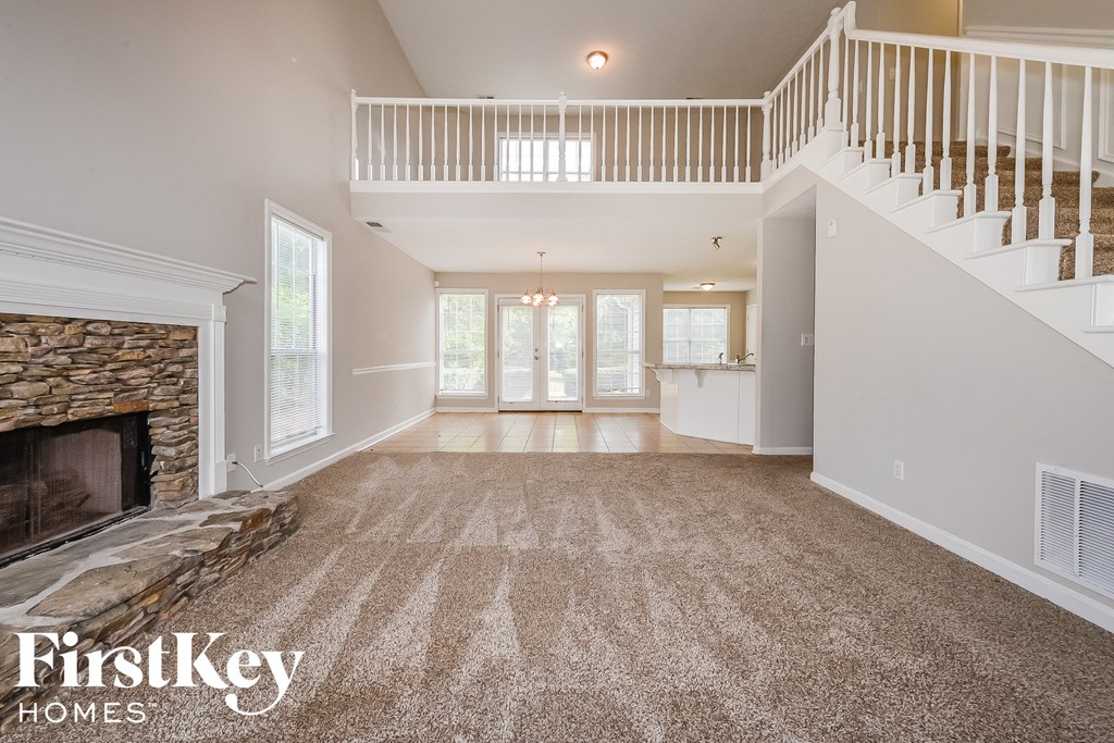 an empty living room with a fireplace and a staircase