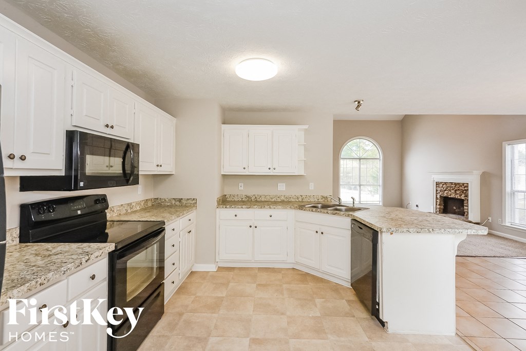 a kitchen with white cabinets and black appliances