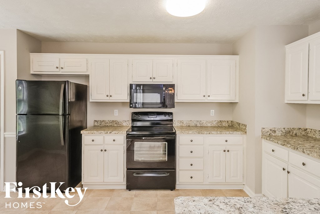 a kitchen with white cabinets and black appliances