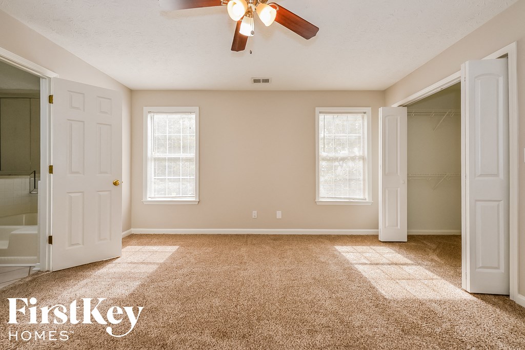 a empty living room with a ceiling fan and a closet