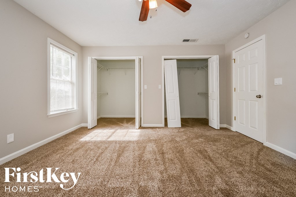 a bedroom with a carpeted floor and two closets and a ceiling fan