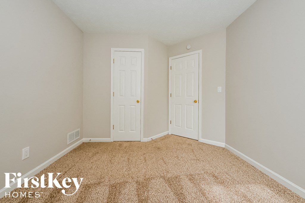 a bedroom with two doors and a carpeted floor