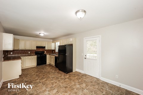 a kitchen with white cabinets and a black refrigerator