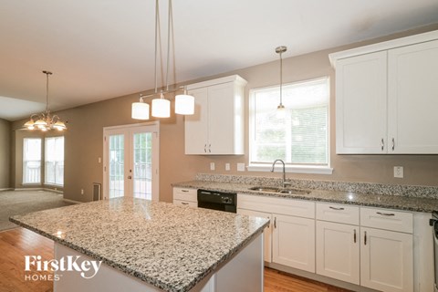 A kitchen with granite countertops and white cabinets.