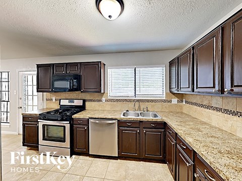 A kitchen with brown cabinets and a granite countertop.