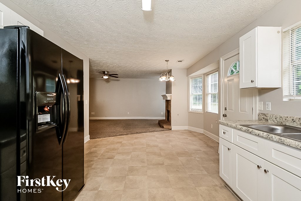 a kitchen with white cabinets and a black refrigerator
