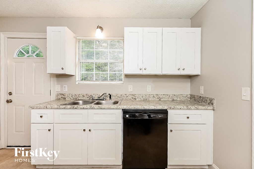a kitchen with white cabinets and a black dishwasher