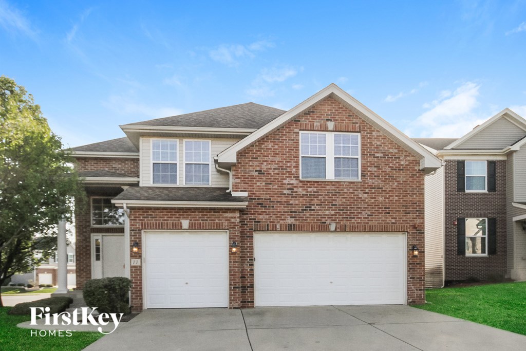 A brick house with two garage doors is for sale.