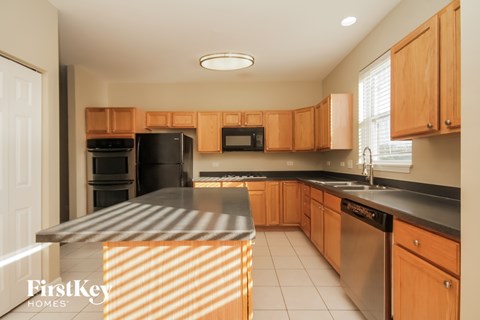 A kitchen with wooden cabinets and a black refrigerator.