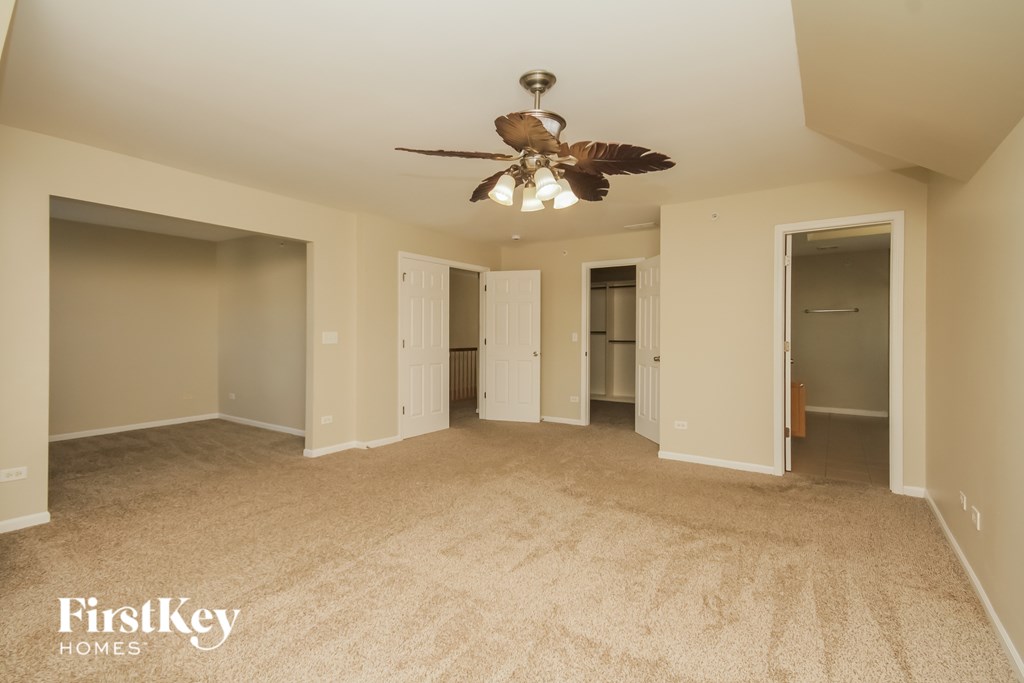 A spacious room with a ceiling fan and beige carpeting.