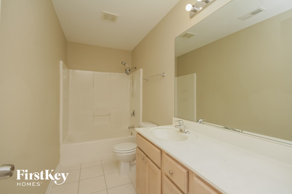 A bathroom with a toilet, sink, and mirror.