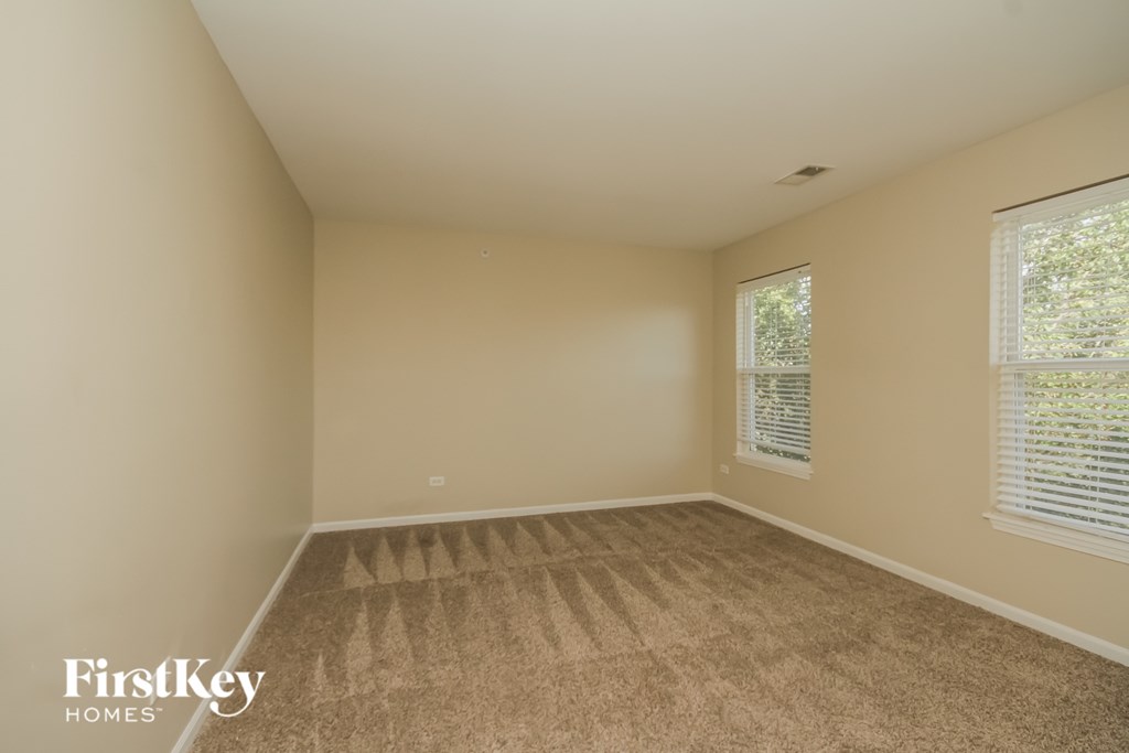 A room with a carpeted floor and a window with blinds.