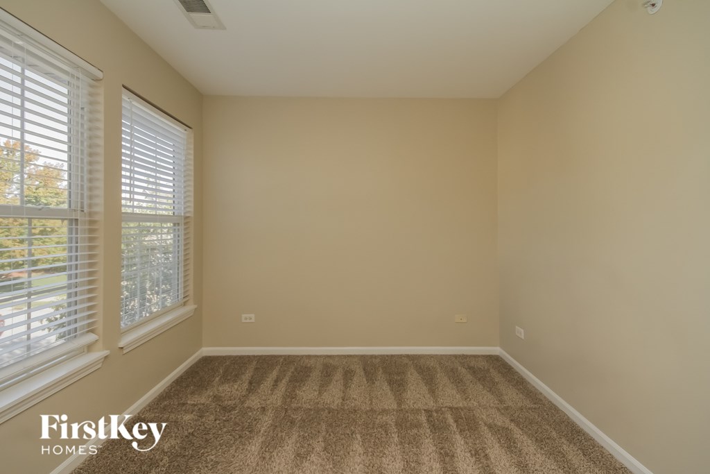 A room with a carpeted floor and a window with blinds.