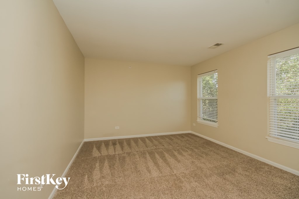 A room with a carpeted floor and a window with blinds.