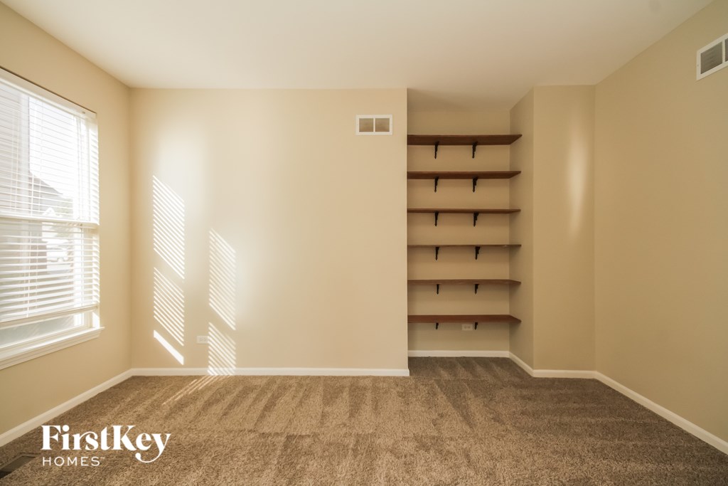 A room with a carpeted floor and a window with blinds.
