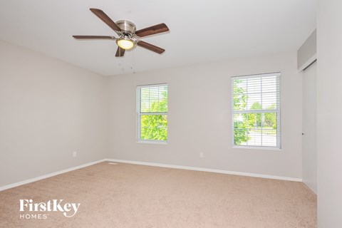 a bedroom with a ceiling fan and two windows