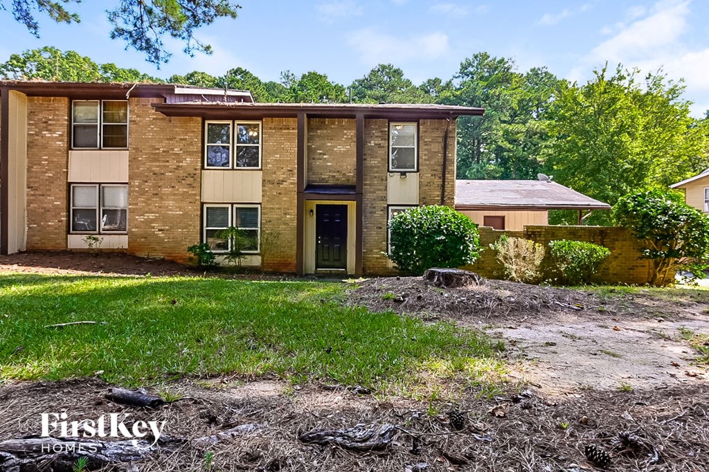 an abandoned house with grass and dirt in front of it