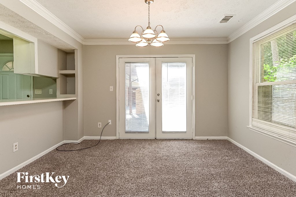 a empty living room with a chandelier and glass doors