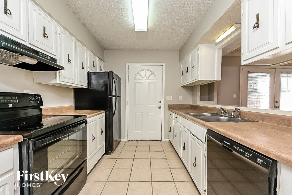a kitchen with white cabinets and black appliances