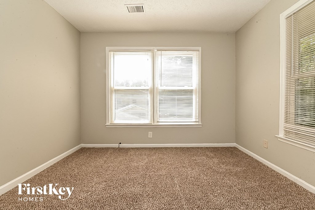 a bedroom with a carpeted floor and two windows