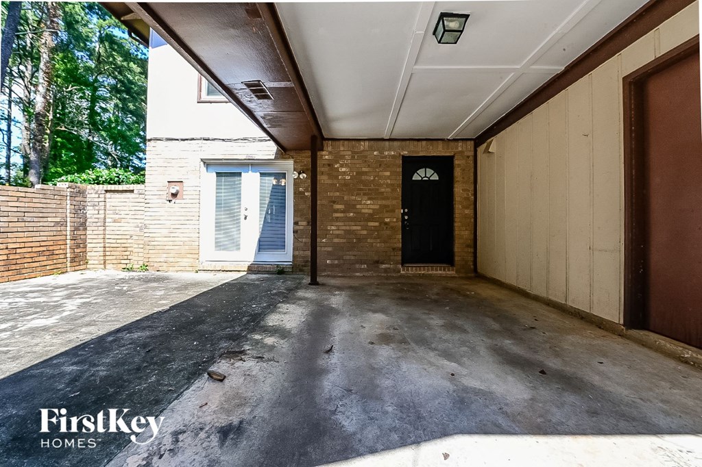 a driveway with a brick wall and a black door