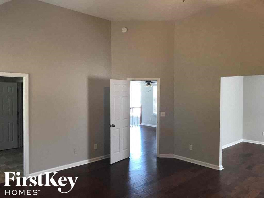 an empty living room with wood floors and a door to a hallway