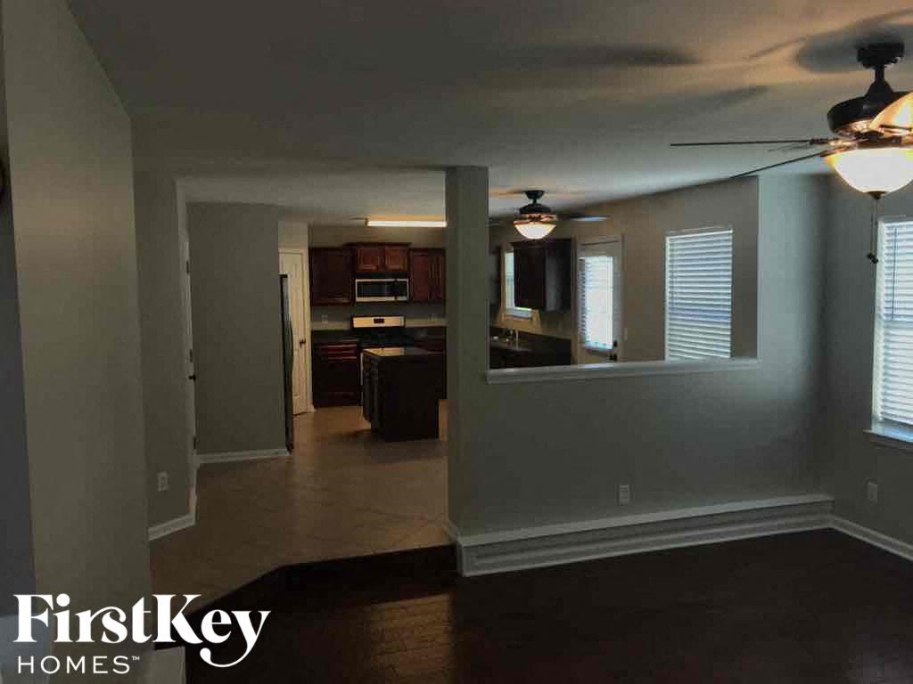 an empty room with a kitchen and a ceiling fan