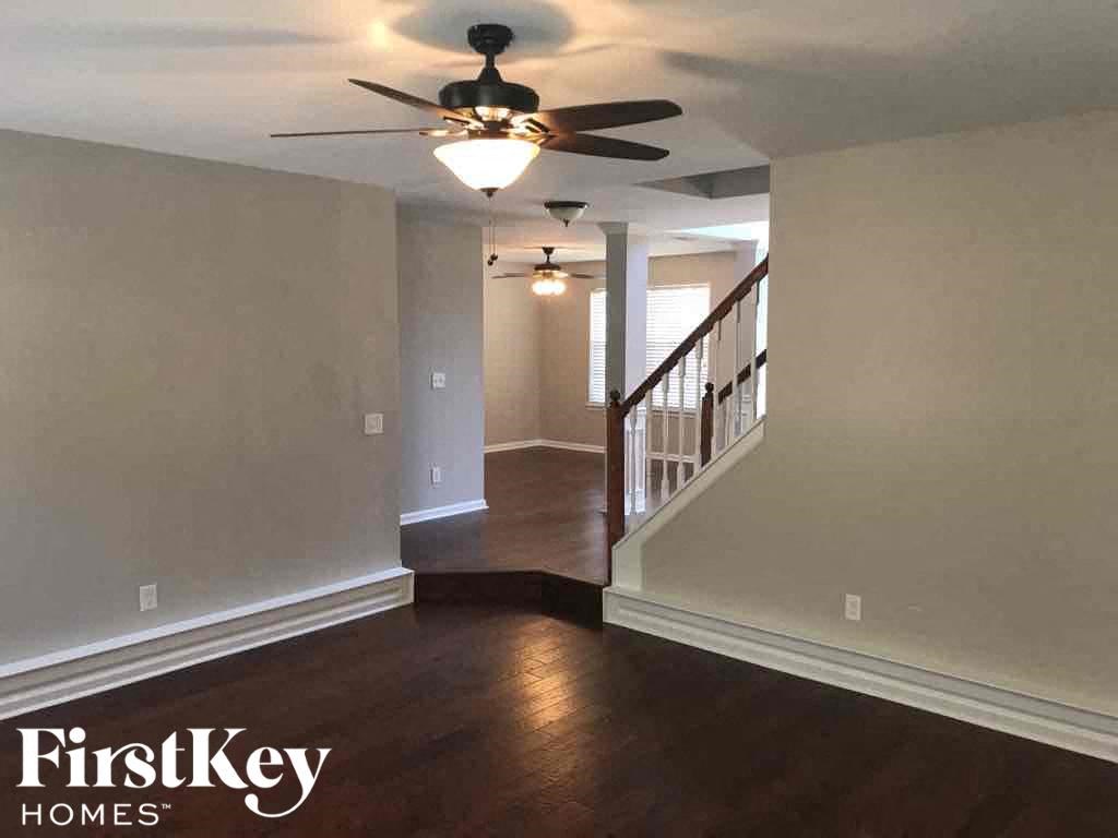 an empty living room with a ceiling fan and a staircase