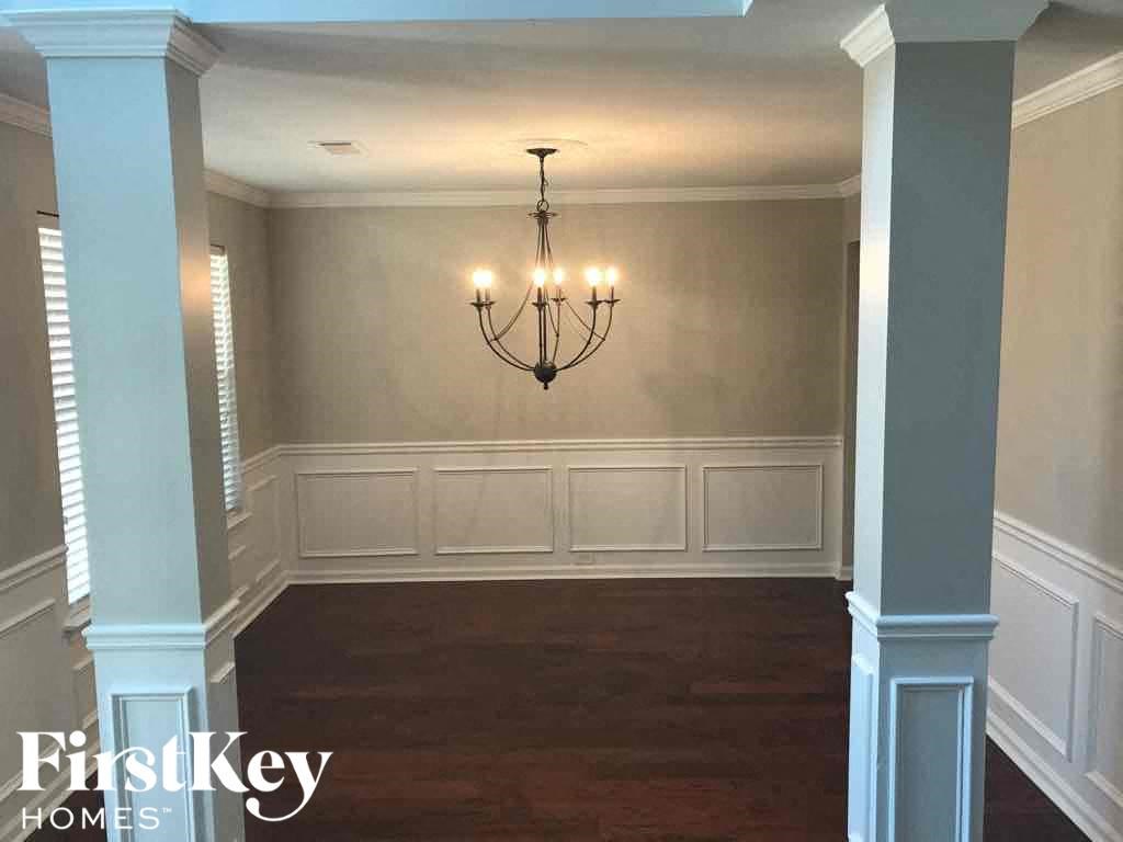 a dining room with white wainscoting and a chandelier
