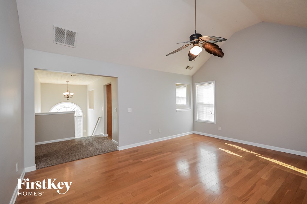 an empty living room with wood floors and a ceiling fan
