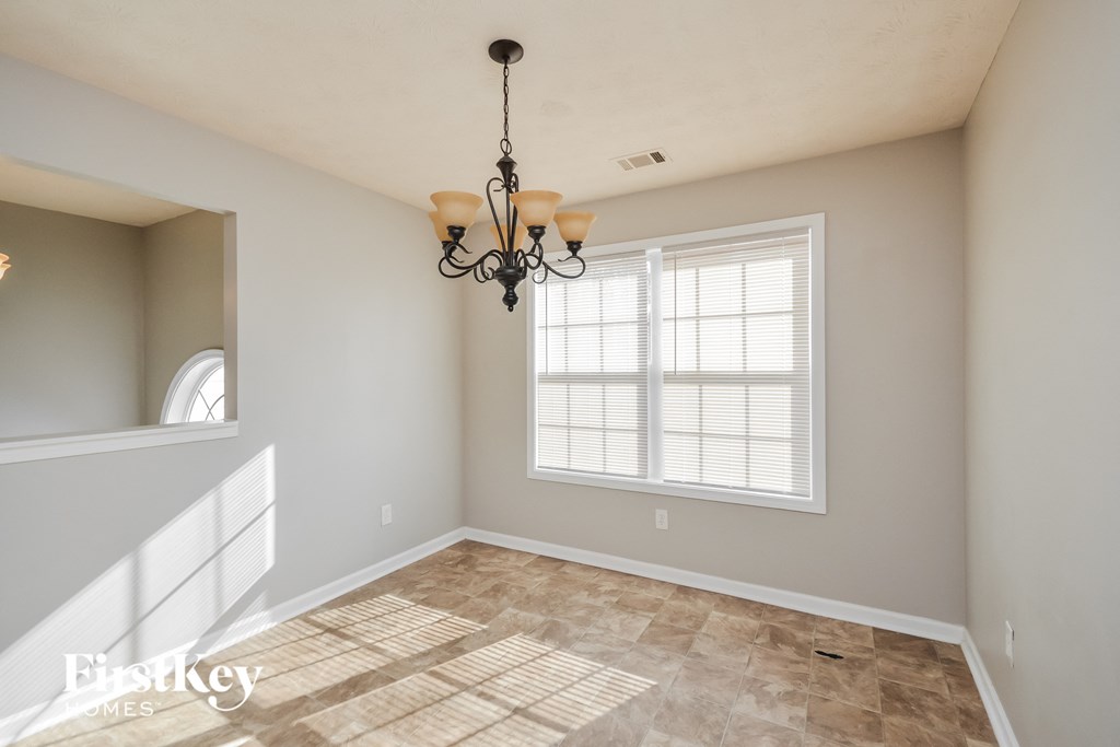 an empty dining room with a chandelier and a window