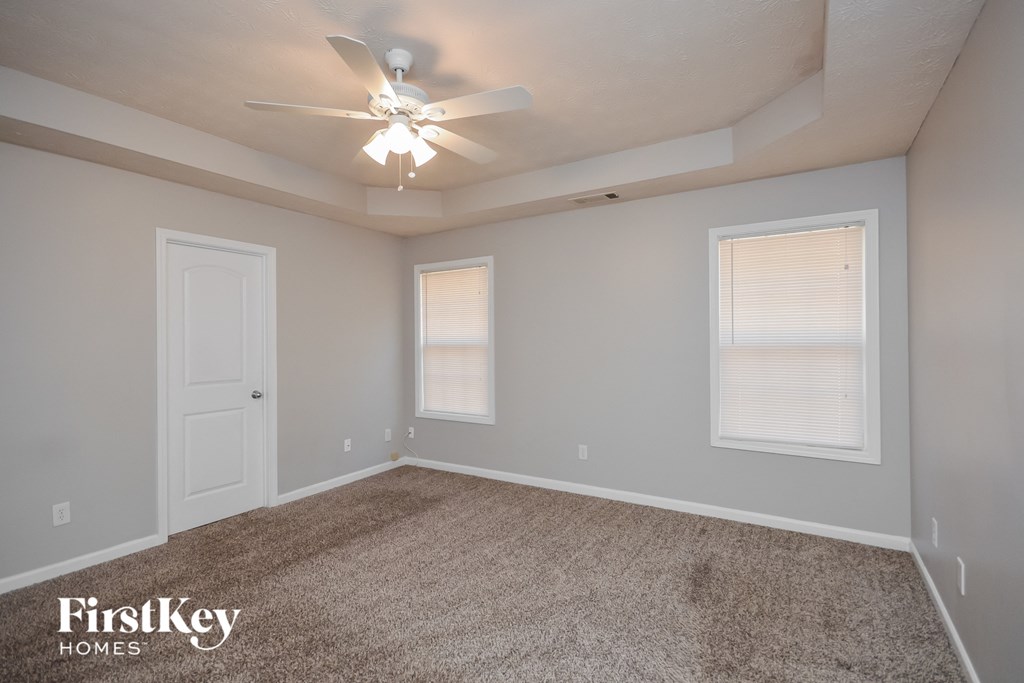 the spacious living room with ceiling fan and window