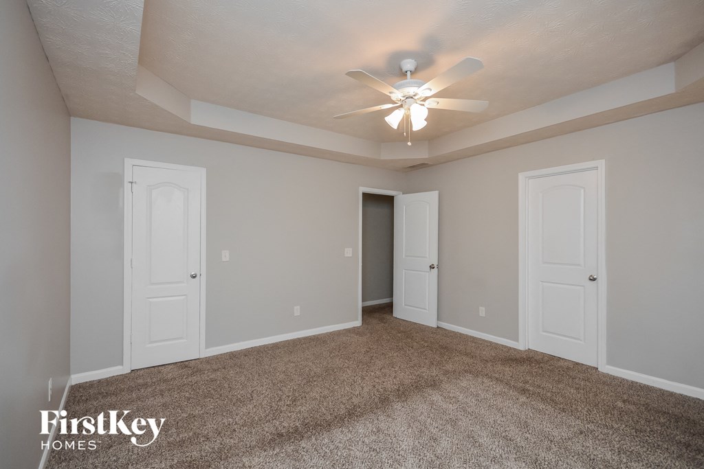 an empty living room with a ceiling fan and white doors