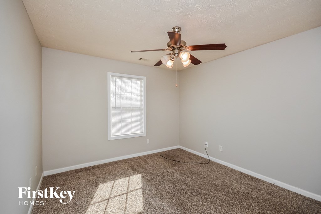the living room is spacious and has a ceiling fan