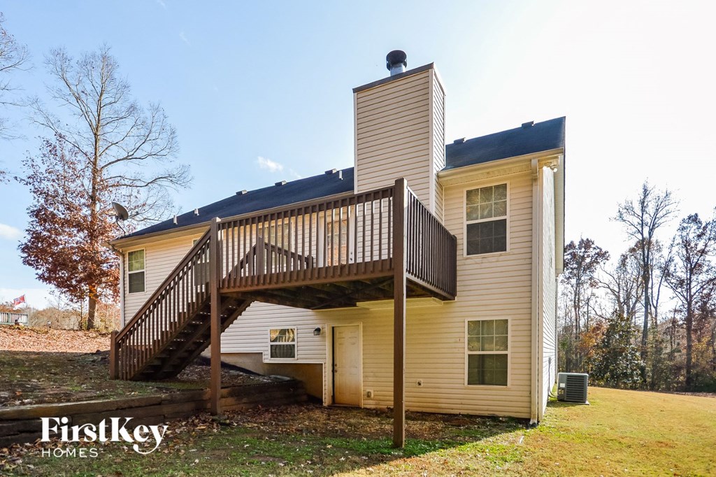 the back of a yellow house with a wooden deck