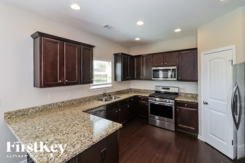 A kitchen with dark brown cabinets and granite countertops.