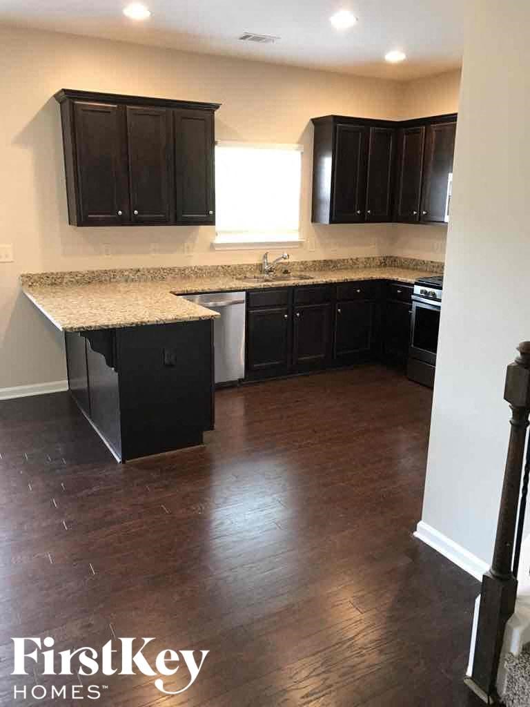 A kitchen with dark wood cabinets and a granite countertop.