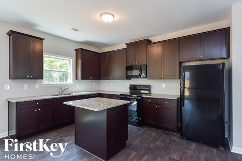 A kitchen with dark wood cabinets and a black refrigerator.