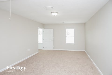 a spacious living room with white carpet and a white door