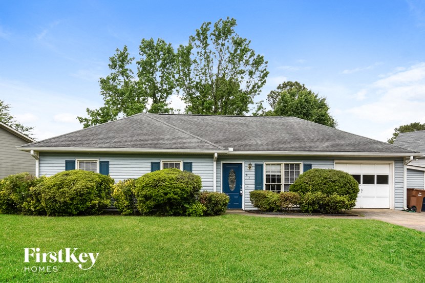 A house with a blue door and a sign that says "FirstKey Homes" in front of it.