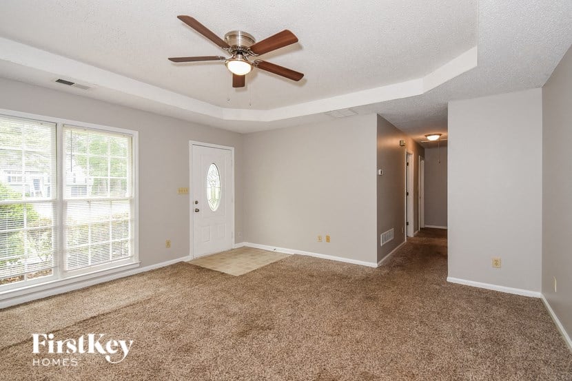 A room with a carpet floor and a ceiling fan.